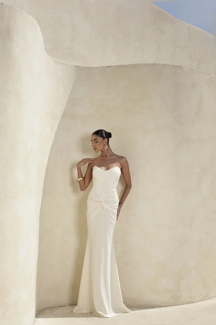 Mulher elegante com vestido branco tomara que caia, estilo minimalista e moderno, em ambiente arquitet&ocirc;nico neutro. Representa tend&ecirc;ncia de vestido de