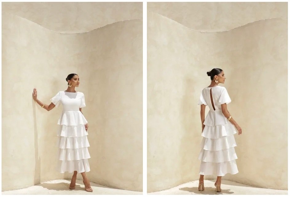 Modelo exibe vestido branco com camadas e mangas curtas em cen&aacute;rio minimalista. Um look para ch&aacute; revela&ccedil;&atilde;o elegante, leve e cheio de delicadeza.