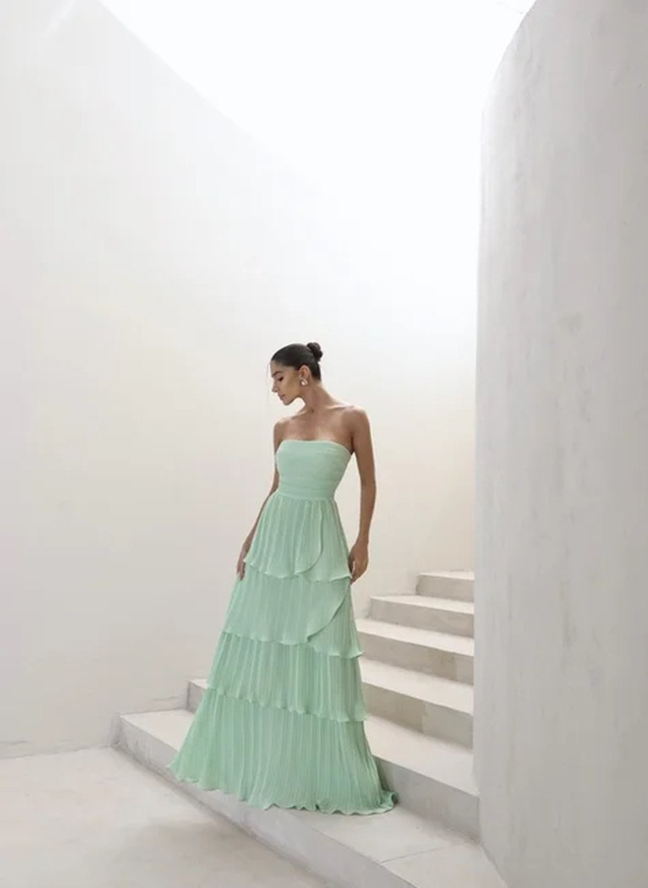 Pessoa em frente a parede de pedra usando vestido para casamento no ver&atilde;o lavanda, tomara que caia, longo e plissado, com