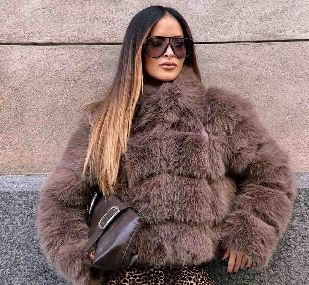 Pessoa com casaco de pele e calça animal print, exibindo looks para inverno europeu em estilo urbano.